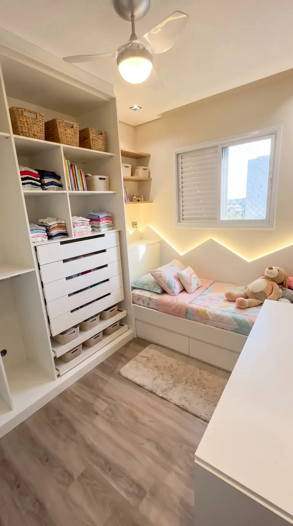 Quarto infantil com guarda-roupa aberto de nichos e gavetas e cama com gavetas
